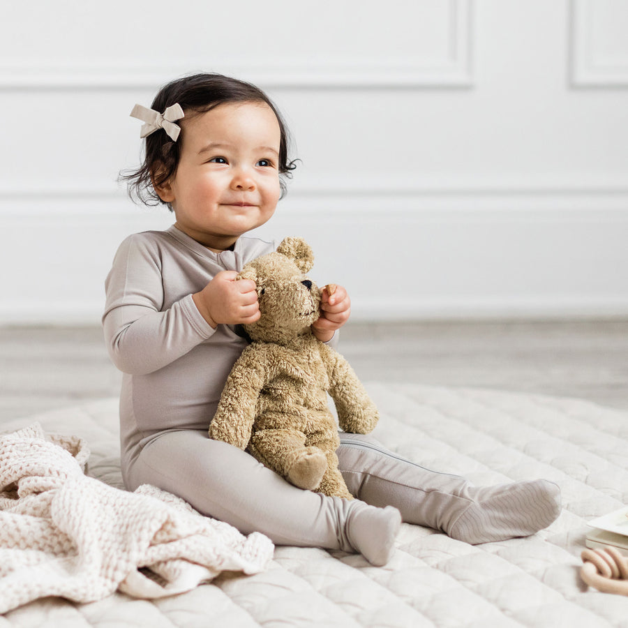 Baby posing on the floor in a soft, organic baby onesie.